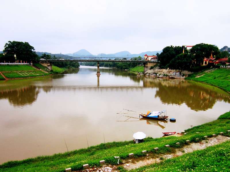 Dòng sông Kỳ Cùng màu phù sa, xa xa là cầu Kỳ Lừa và bờ cỏ xanh